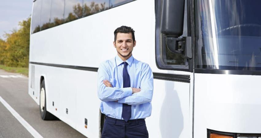 A charter bus driver in front of a bus